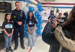  Officer Vigradamo poses for picture with two 6th graders in front of blue balloon arch